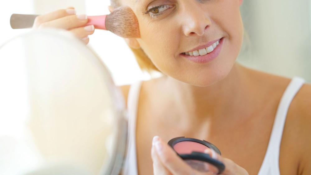 A woman applying powder blush.