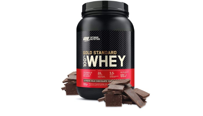 a large container of Optimum Nutrition Gold Standard whey protein powder with chocolate pieces stacked around it