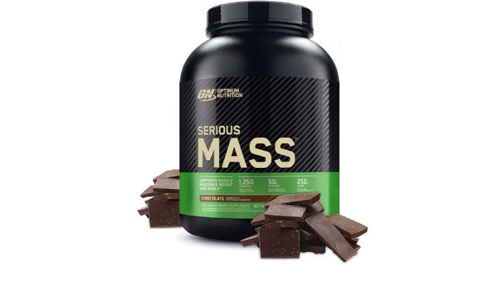 A large black container of Optimum Nutrition Serious Mass protein powder with pieces of chocolate around it