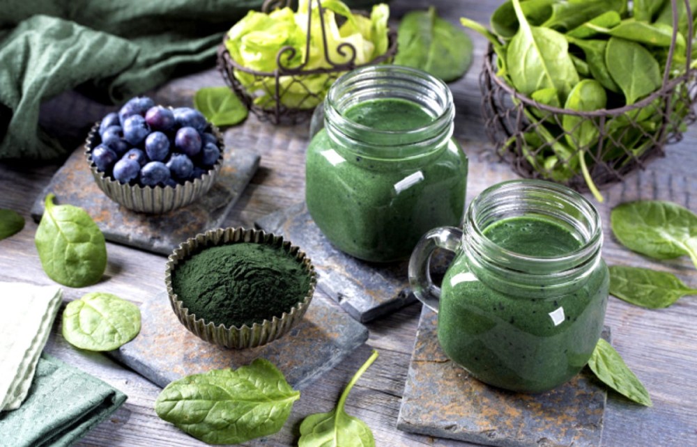 Green smoothies with spirulina powder,spinach, and blueberries on the table