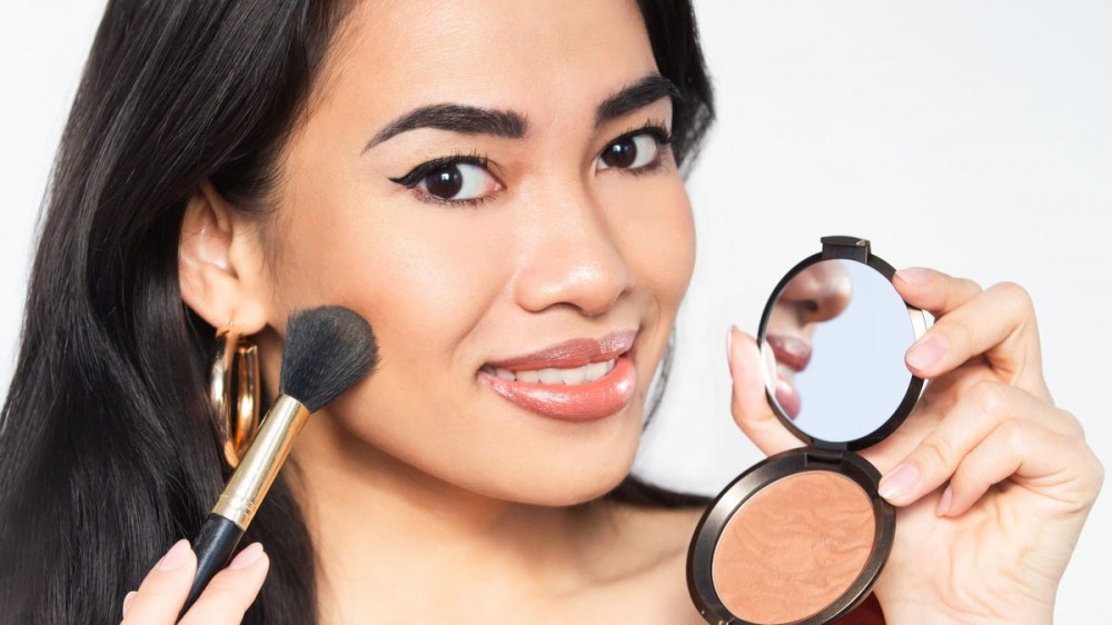 Woman applying bronzer with a brush.