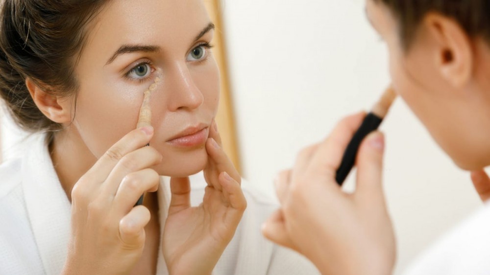 Woman using concealer for under-eye circles.