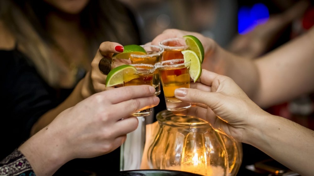 People cheers using tequila shots with lime.