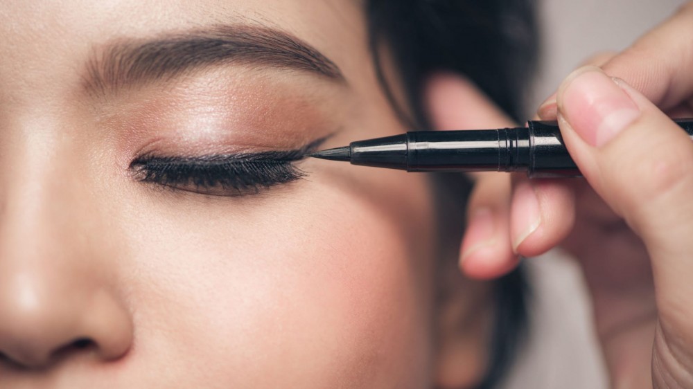 A close-up of woman applying eyeliner.