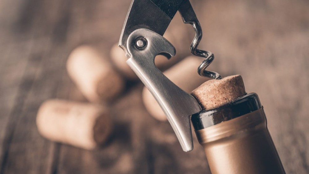 A corkscrew is inserted into a cork in a bottle of wine.