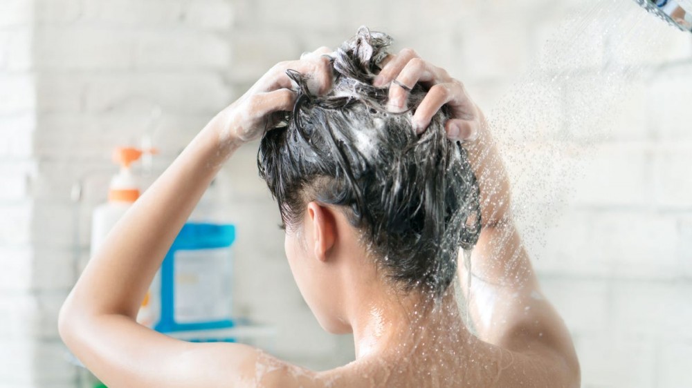 A woman washes her hair in the shower.