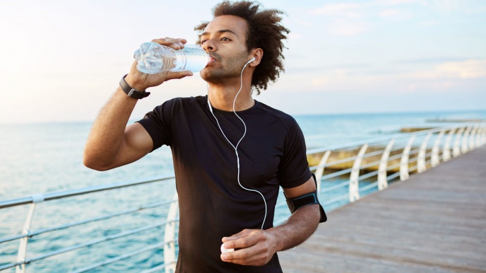 A man drinks from a water bottle while working out.