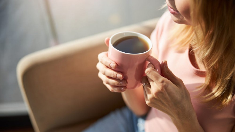 A woman holds a coffee mug.