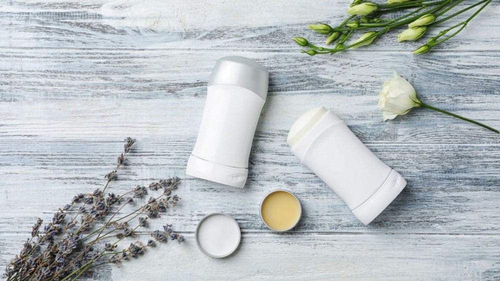 Two canisters of deodorant sit on a wooden surface.