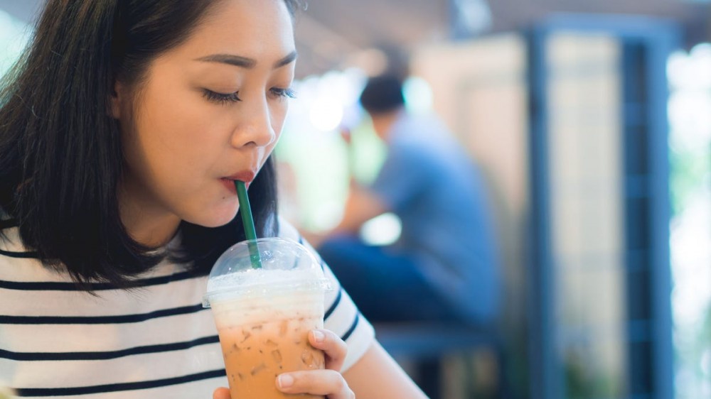 A woman drinks iced coffee from a straw.