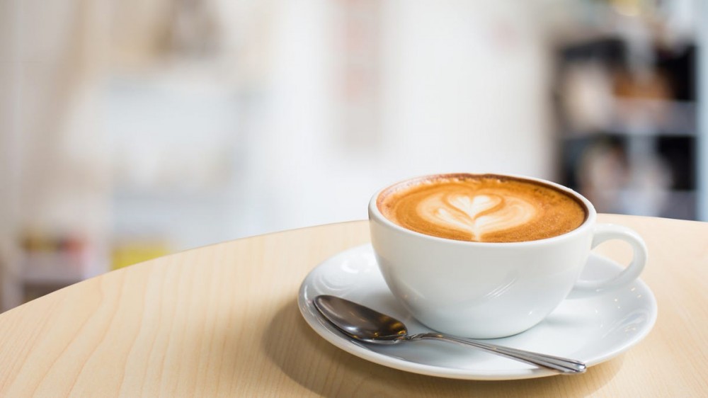 A latte in a large white coffee mug sits on a counter.