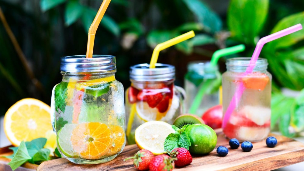 Mason jar drinking glasses are filled with fruit and infused water.