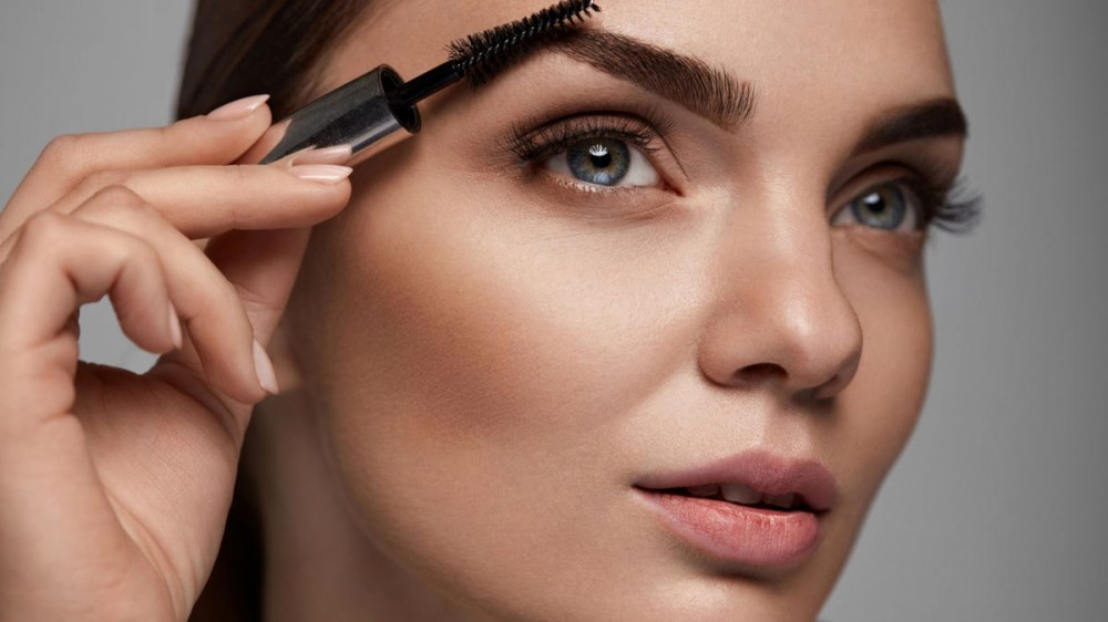 Close-up of woman putting on eyebrow gel.