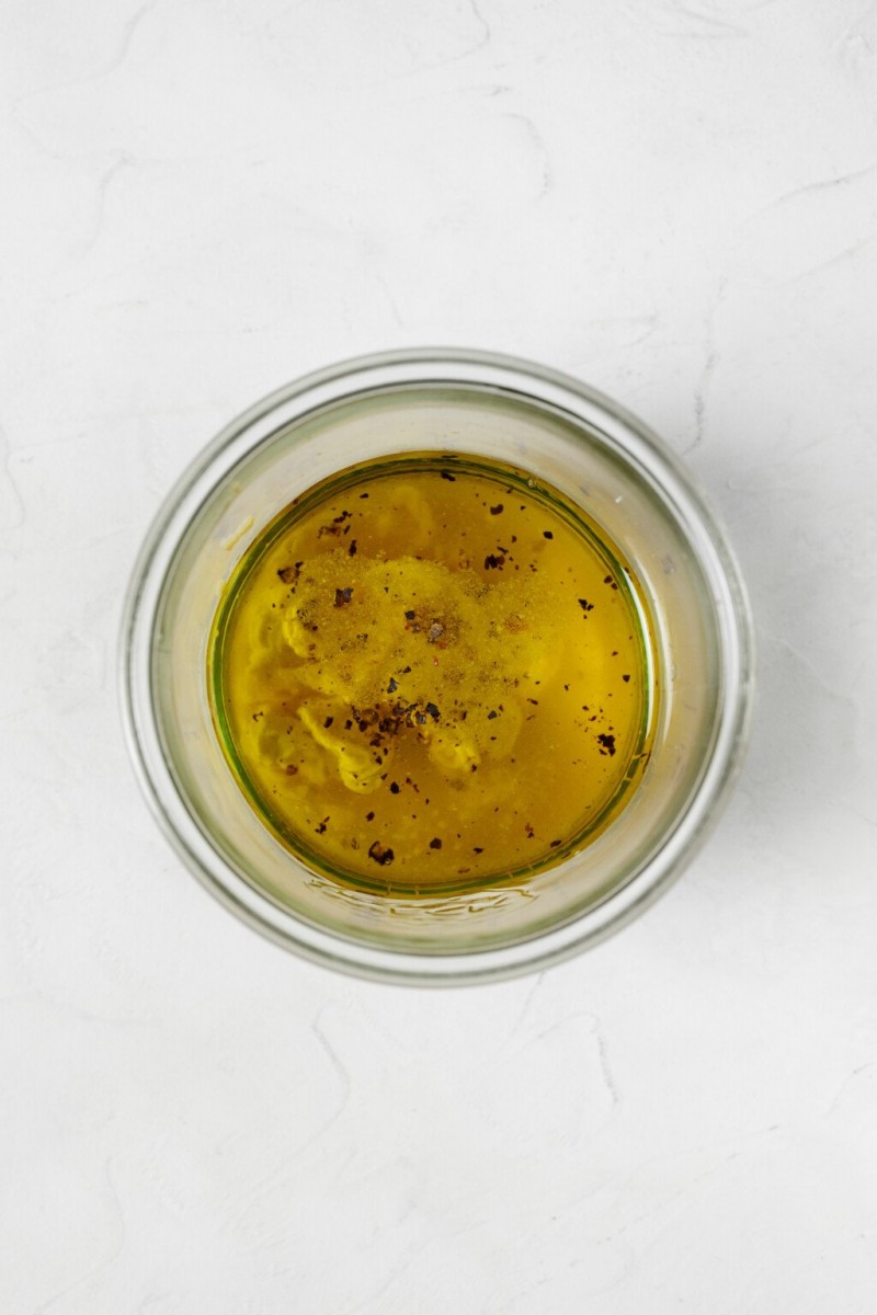 An overhead image of the ingredients for a vinaigrette, which are in a mason jar before mixing.