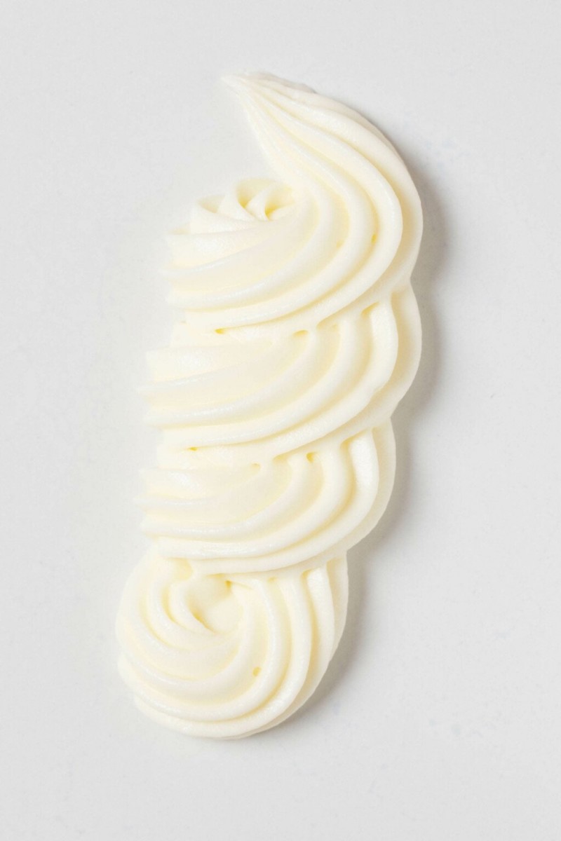 An overhead image of a squiggle of vegan cream cheese frosting, piped onto a flat white surface.