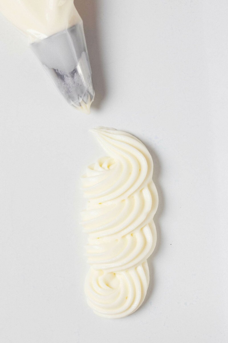 An overhead image of a squiggle of vegan cream cheese frosting, piped onto a flat white surface.