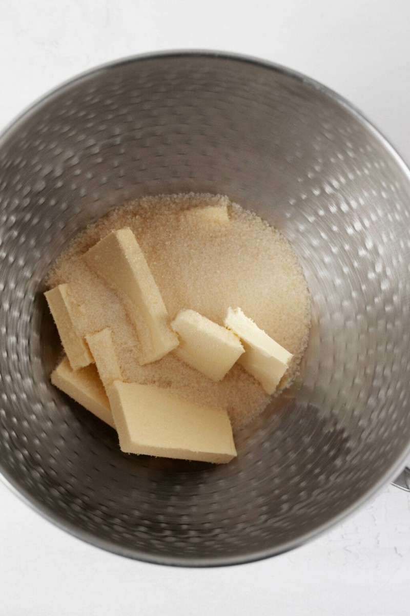 A large, silver bowl is pictured with butter and sugar inside it.